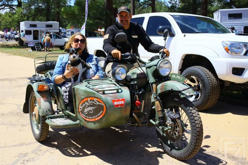 Dog rides in motorcycle sidecar with woman and man