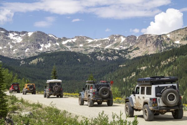 A convoy of Jeep on dusty mountain road.