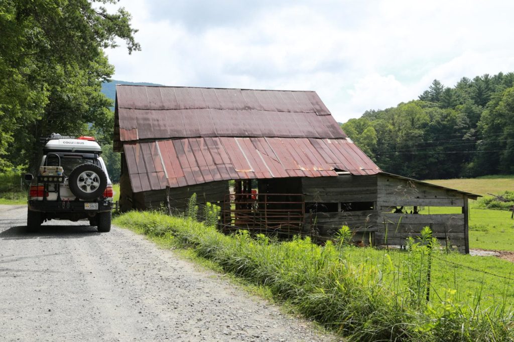 A 100 Series Toyota Landcruiser passing an old barn on the Georgia Traverse.