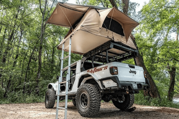 Jeep Gladiator with bed rack and rooftop tent in the forest.