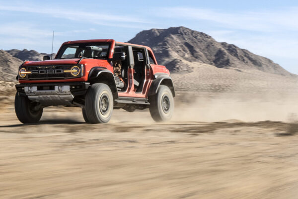 2022 Ford Bronco Raptor driving high-speed through the desert.