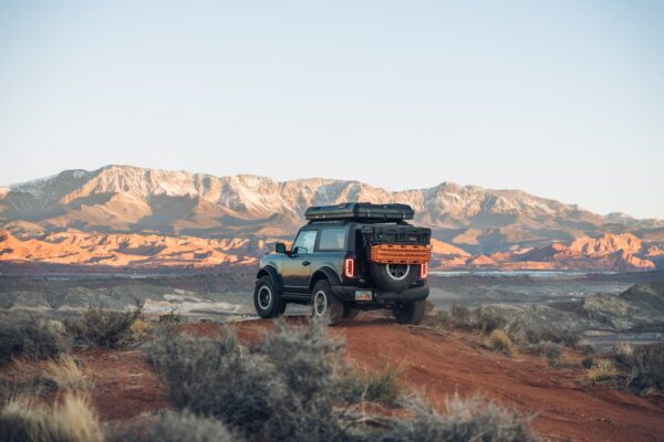 The ROAM Rambler Hardshell Rooftop Tent on a Ford Bronco driving in the desert.