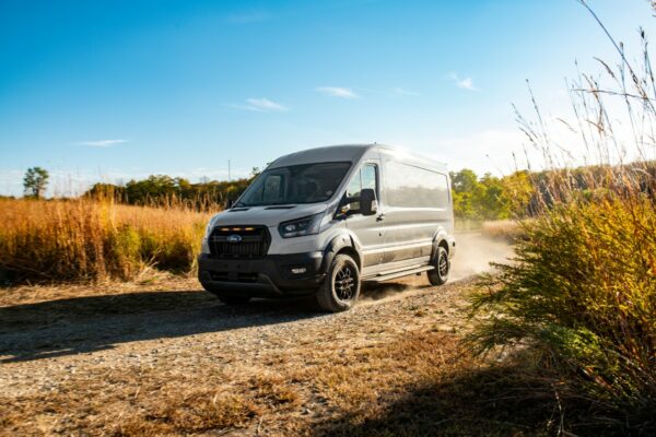 2023 Ford Transit Trail kicks up dust on a dirt road.