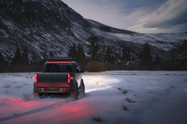 Canoo Pickup driving through snow in the mountains.